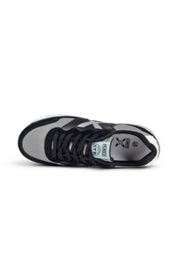 Zapatilla negra y gris con un upper de ante y malla, que presenta un diseño de cordones, suela de goma y logo de la marca visible en la lengüeta.