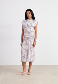 Pink patterned dress with short sleeves, ruched waist, mid-length hem, and slit. Worn with light-colored flat shoes. Smooth fabric texture.