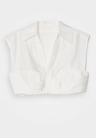 Blouse blanche courte en tissu léger, avec un col, des manches courtes et une fermeture à boutons sur le devant avec des accents plissés.