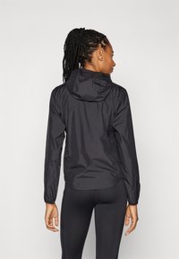 Μαύρο ελαφρύ μπουφάν με κουκούλα, ελαστικά μανίκια και καμπυλωτό τελείωμα, που παρουσιάζει ομαλή υφή και μινιμαλιστικό σχεδιασμό.