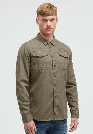 Olive green button-up shirt, long sleeves, two front pockets, subtle branding on the chest, textured fabric, slightly relaxed fit.