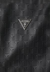 Geantă de umăr texturată, neagră, cu un model geometric, detalii în relief și un logo metalic triangular. Fabricată din material sintetic.