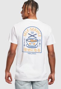 Weißes Baumwoll-T-Shirt mit buntem Grafikdesign eines lächelnden Ramen-Schalen, Essstäbchen und japanischem Text, mit rundem Design auf der Rückseite.