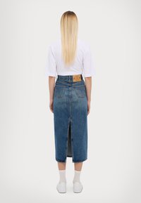 Sinine denim midi seelik, millel on taga lõhik, kõrge vöökoht, viis taskut ja nahast brändi silt seljal.