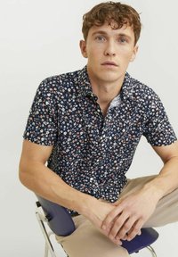 Camicia a maniche corte di colore blu navy con un motivo floreale in bianco, arancione e rosa. Design con colletto e bottoni, caratterizzata da una texture di cotone morbida.