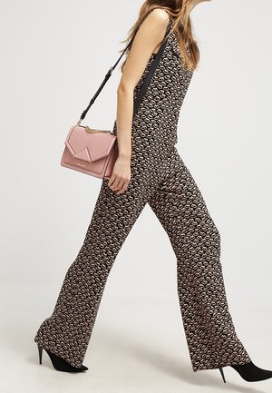 Musta haalari, jossa on kermaan vivahtava sydänkuvio, levenevät lahkeet ja hihaton malli. Mukana vaaleanpunainen olkalaukku.