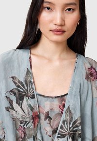 Kimono leggero con motivo floreale in morbido turchese, con maniche ampie e fluide, caratterizzato da intricati disegni di foglie e orchidee in colori tenui.