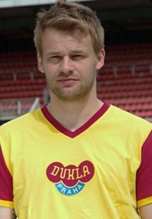 Geel sporttricot met rode accenten en een V-hals ontwerp, met een logo met "DUKLA PRAHA" in vette letters aan de voorkant.