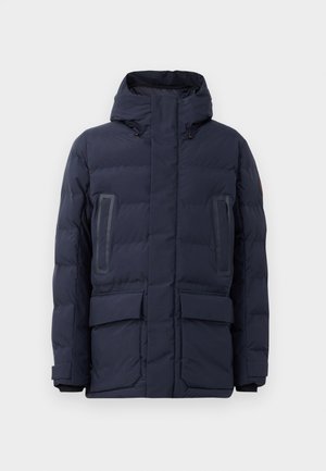 Doudoune marine avec un col montant, capuche réglable, deux poches à l'avant et des accents de panneaux contrastants sur la poitrine.
