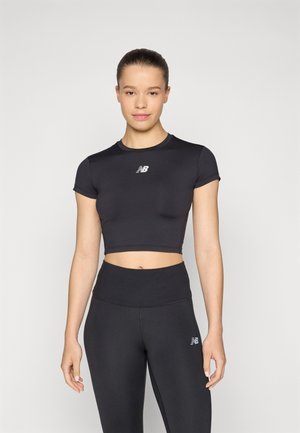 Crni sportski crop top s kratkim rukavima, sa malim bijelim logotipom na prsima. Uparen s crnim tajicama visokog struka.