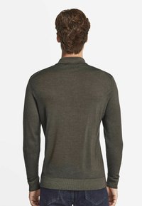 Mörkgrön långärmad tröja med krage, ribbade ärmslut och nederkant. Slät textur med en figurnära design och minimalt med detaljer.