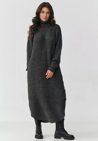 Długi, oversize'owy sweter sukienka w ciemnoszarym kolorze z teksturowanym, dzianinowym wzorem. Posiada wysoki golf i długie rękawy.