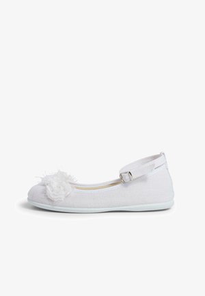 Bílé baletní boty vyrobené z texturované látky s měkkým chlupatým pom-pom detailem na špičce a nastavitelným páskem kolem kotníku. Plochá podešev.