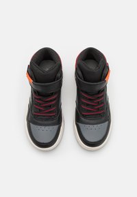 Une paire de baskets montantes noires et grises avec des détails rouges, des lacets rouges et noirs, et des accents oranges sur un fond blanc.