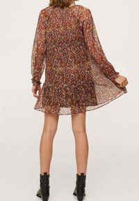 Vestido mini floral en tejido marrón transparente con patrones multicolores. Presenta mangas largas, detalles de puños fruncidos y una silueta de falda acampanada.