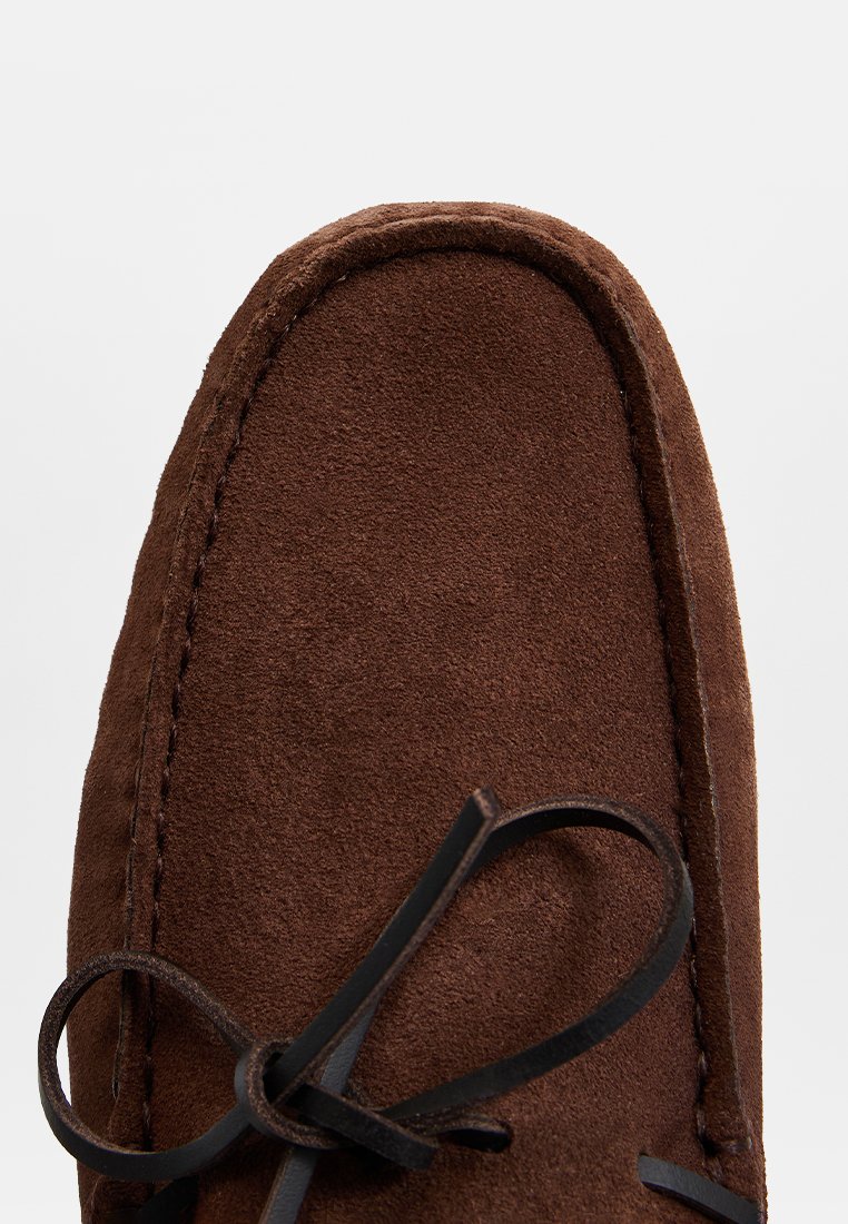 Braune Wildleder-Mokassinschuhe mit runder Zehenform, kontrastierenden Nähte und einer schwarzen Schnürung, die vorne gebunden ist, und die eine weiche Textur zeigen.