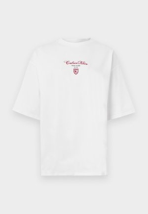 T-shirt branca de manga curta oversized com texto vermelho "Calvin Klein New York EST 1968" e um pequeno logótipo de escudo no peito.