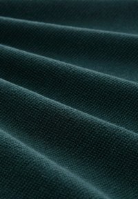 Tejido texturizado en azul oscuro, con apariencia tejida, que muestra ondas horizontales y diferentes reflejos de luz en la superficie.