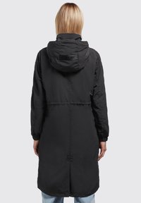 Black long coat with a hood, featuring cinched waist, elastic cuffs, and a logo patch at the back. Smooth, lightweight material.