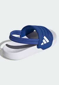 Modra natikača s teksturiranim zgornjim delom in belim podplatom; ima dva paščka za oporo in poudarek z blagovno znamko na strani.