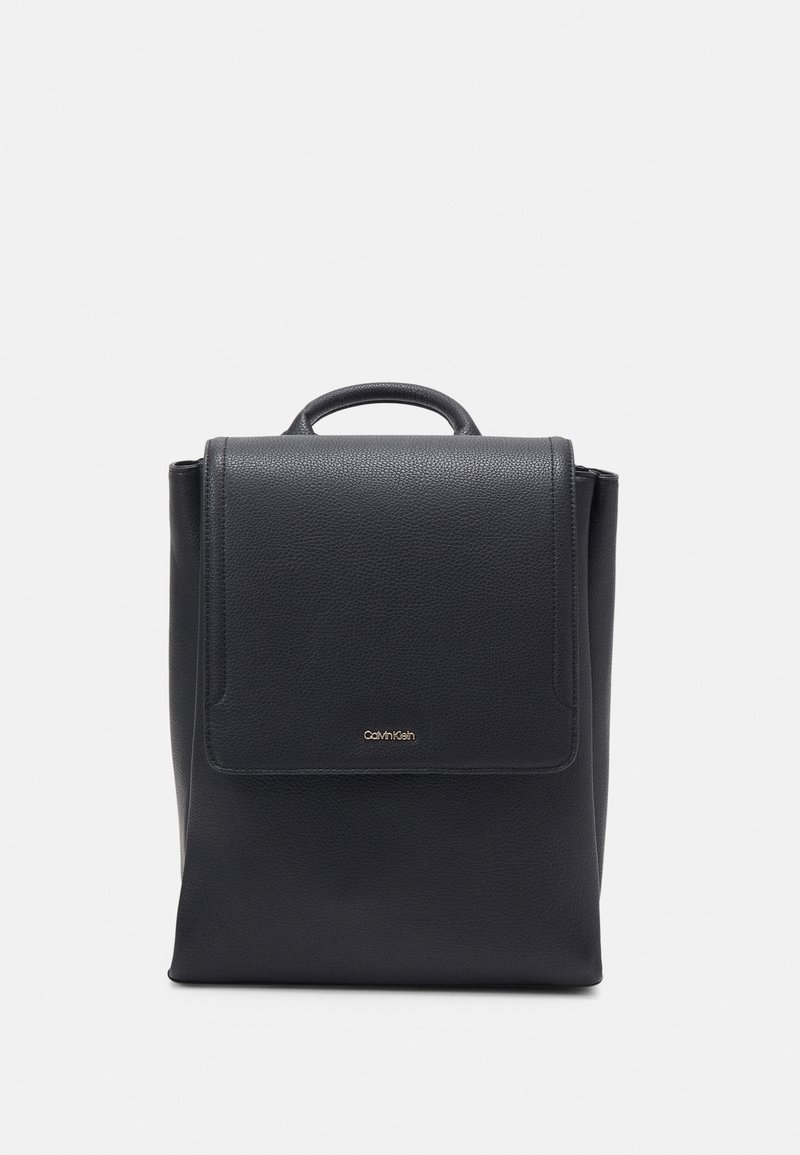 Sac à dos en cuir noir avec poignée supérieure, fermeture à rabat et petit logo Calvin Klein doré au centre avant.