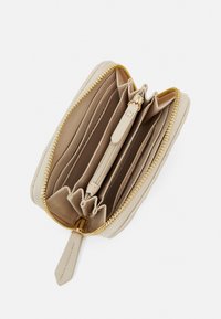 Beige lynlås tegnebog med flere kortlommer og rum. Glat tekstur og hardware med guldfarvet lynlås. Minimalistisk design.