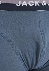 Ropa interior para hombre de algodón azul oscuro, con una cinturilla suave y elástica, adornada con letras en blanco. Textura suave con costuras planas.