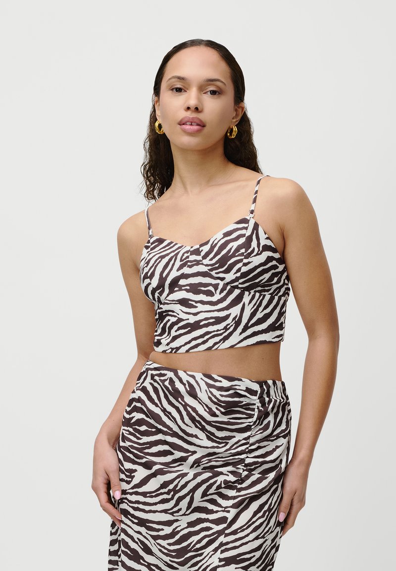 Hnedo-biely crop top so vzorom zebry s tenkými ramienkami, ktorý má priliehavý strih a hladkú textúru, v komplete s ladiacou sukňou.
