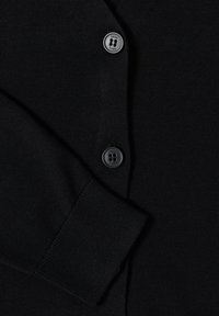 Cardigan en tricot noir avec poignets côtelés et deux boutons noirs gravés du nom de la marque "CECIL".