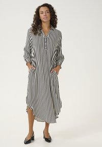 Striped shirt dress in black and cream with a collared neckline, button placket, side pockets, and cuffed balloon sleeves.