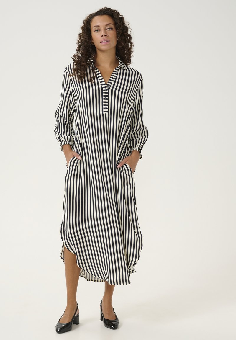 Striped shirt dress in black and cream with a collared neckline, button placket, side pockets, and cuffed balloon sleeves.