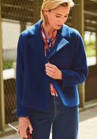 Marineblauwe wollen jas in een blend met een notch-kraag, dubbele knopenrij aan de voorkant en grote knopen. Gelaagd over een gebloemde blouse. Casual pasvorm.