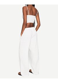 Vita linnevida byxor med elastisk midja och sidofickor, ihop med en åtsittande vit smockad crop top.