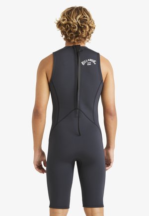 Traje de neopreno negro con diseño sin mangas y pierna hasta la rodilla. Presenta un zipper en la parte posterior y un logo blanco en la parte superior de la espalda. Textura suave.