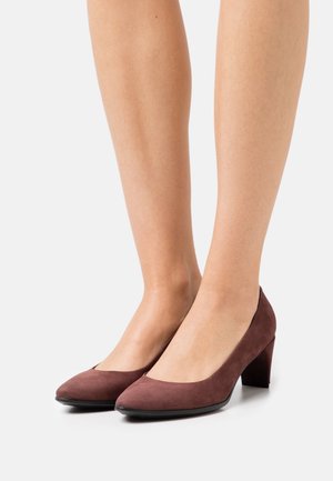 Escarpins en daim bordeaux à talon haut avec un dessus incurvé, un bout arrondi et un talon bloc de hauteur intermédiaire. Texture lisse et design minimaliste.