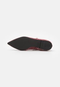 Bordowe baleriny z aksamitu o spiczastym nosku i gładkiej czarnej podeszwie. Zawierają subtelne logo na podeszwie.