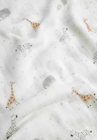 Biela mušelínová tkanina so hravými potlačenými zvieratami, vrátane žiráf, zebier a slonov, s jemným vzorom hviezd.