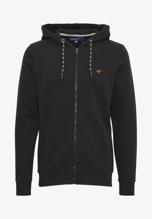 Black zip-up hoodie made of soft fabric. Features a drawstring hood, logo patch on chest, and front pockets. Cuffs are fitted.