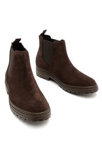 Brązowe zamszowe botki za kostkę z elastycznymi panelami bocznymi, zaokrąglonym czubkiem i teksturowaną gumową podeszwą, z pętelką do zakupu z tyłu.