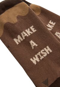 Calcetines marrones con una textura suave, que presentan la frase "HAZ UN DESEO" en letras blancas y un patrón de puntos en tonos más claros.