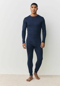 Marineblaues Langarmshirt und passende Leggings aus weichem, dehnbarem Stoff. Eng anliegendes Design mit Rundhalsausschnitt und gerippter Struktur.