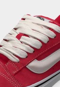 Κόκκινο σουέτ αθλητικό παπούτσι με λευκά κορδόνια, λευκή πλευρική γραμμή και μαύρες λεπτομέρειες. Ο σχεδιασμός περιλαμβάνει εμφανή ραφές και υλικά με υφή.