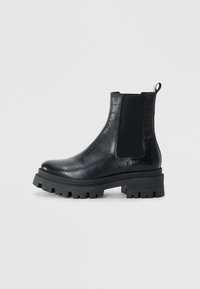 Bottines en cuir noir avec texture crocodile, panneaux latéraux élastiques et semelle à traction robuste. Étiquette à l'arrière pour un enfilage facile.