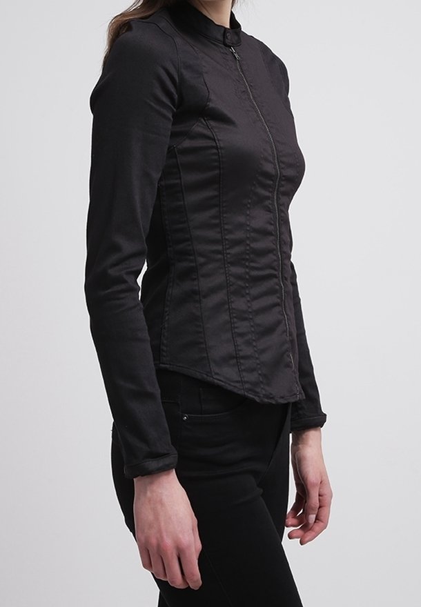 Giacca nera a maniche lunghe con colletto alto, design aderente e zip frontale. Presenta cuciture a contrasto e una texture liscia.