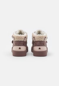 Bottes en peluche de couleur marron avec doublure beige douce, bout arrondi et accents roses contrastants ; elles présentent des oreilles et des détails faciaux.