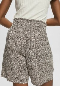Pantaloni corti a righe bianche e nere con vita elastica, realizzati in un tessuto leggero. Presentano una vestibilità ampia e nessuna tasca visibile.