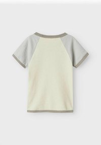 Camiseta de manga corta en crema con mangas raglán gris claro. Presenta un cuello redondo y un ribete acanalado. Textura de tela de punto suave.