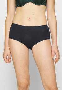 Culottes en coton noir taille haute avec des bordures festonnées à la taille et aux jambes, présentant une texture lisse et un design classique.