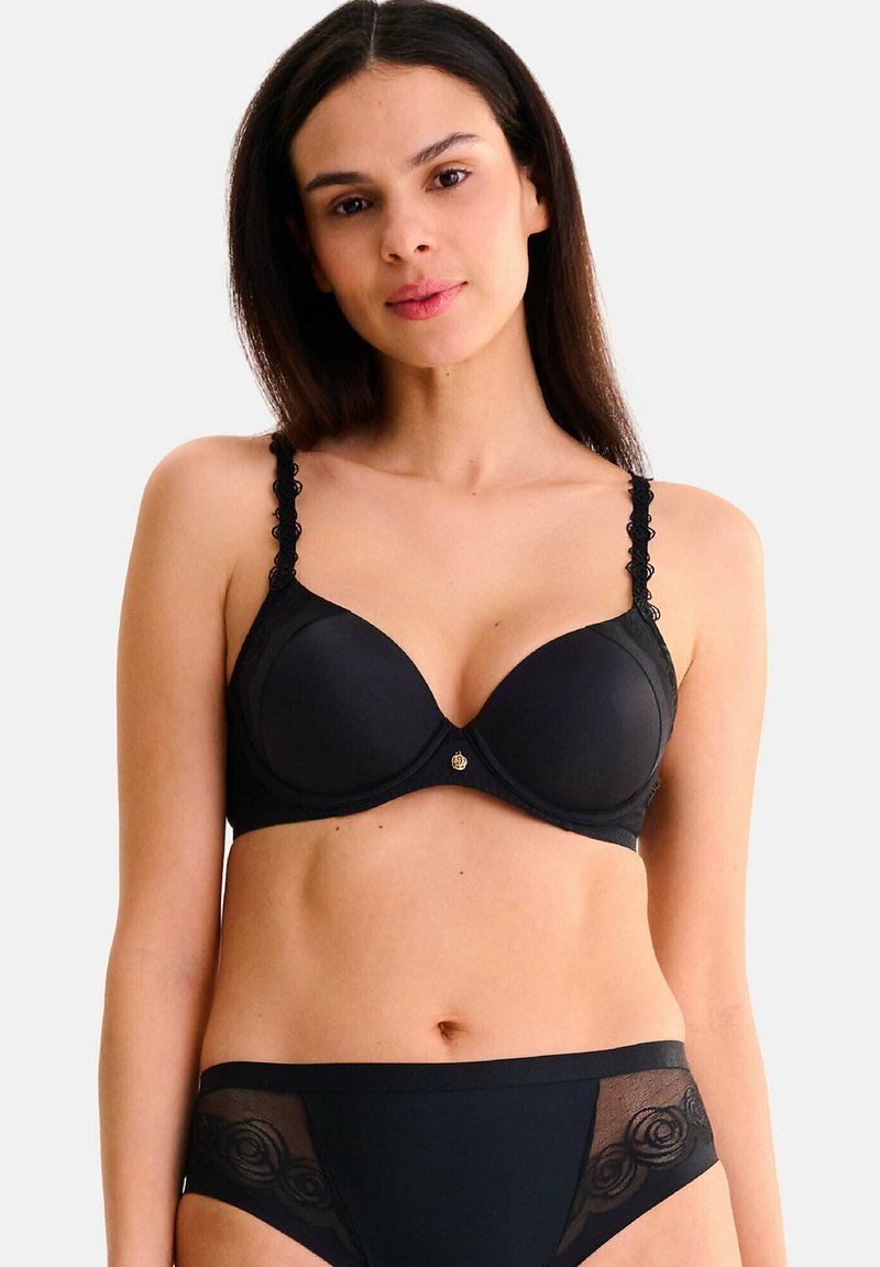 Soutien-gorge noir avec bonnets rembourrés et bretelles en dentelle festonnée, orné d'un détail central en métal doré. Culotte taille haute assortie avec accents transparents.