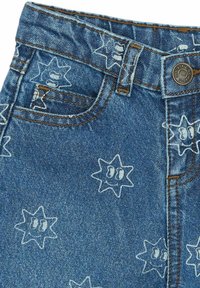 Tumed sinised denim lühikesed püksid, millel on tähtede muster, kus on naeratavad näod. Sisaldab esist pocketi ja nähtavat kontrastset pruuni õmblust.